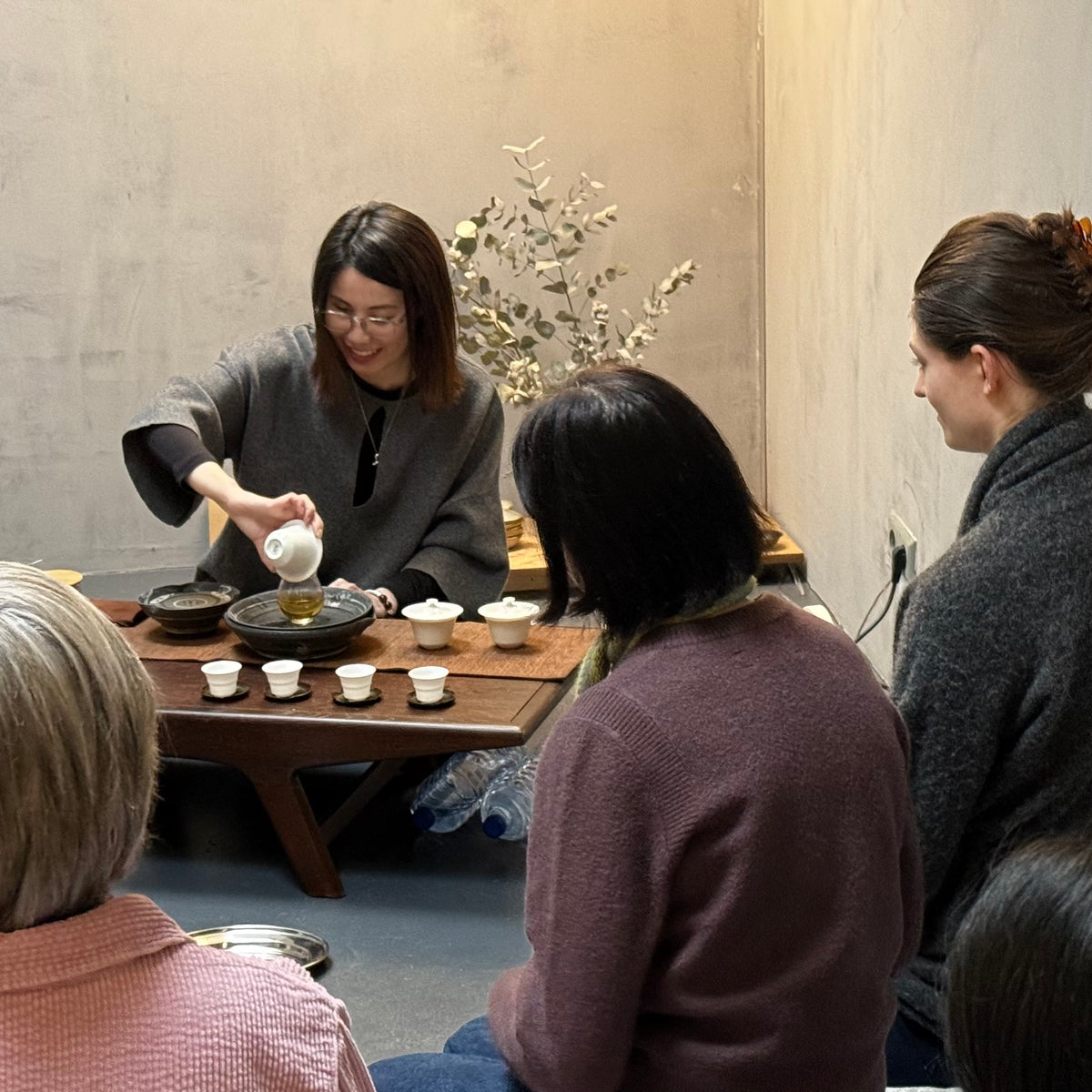 Group of people gathered around a table for a tea ceremony.