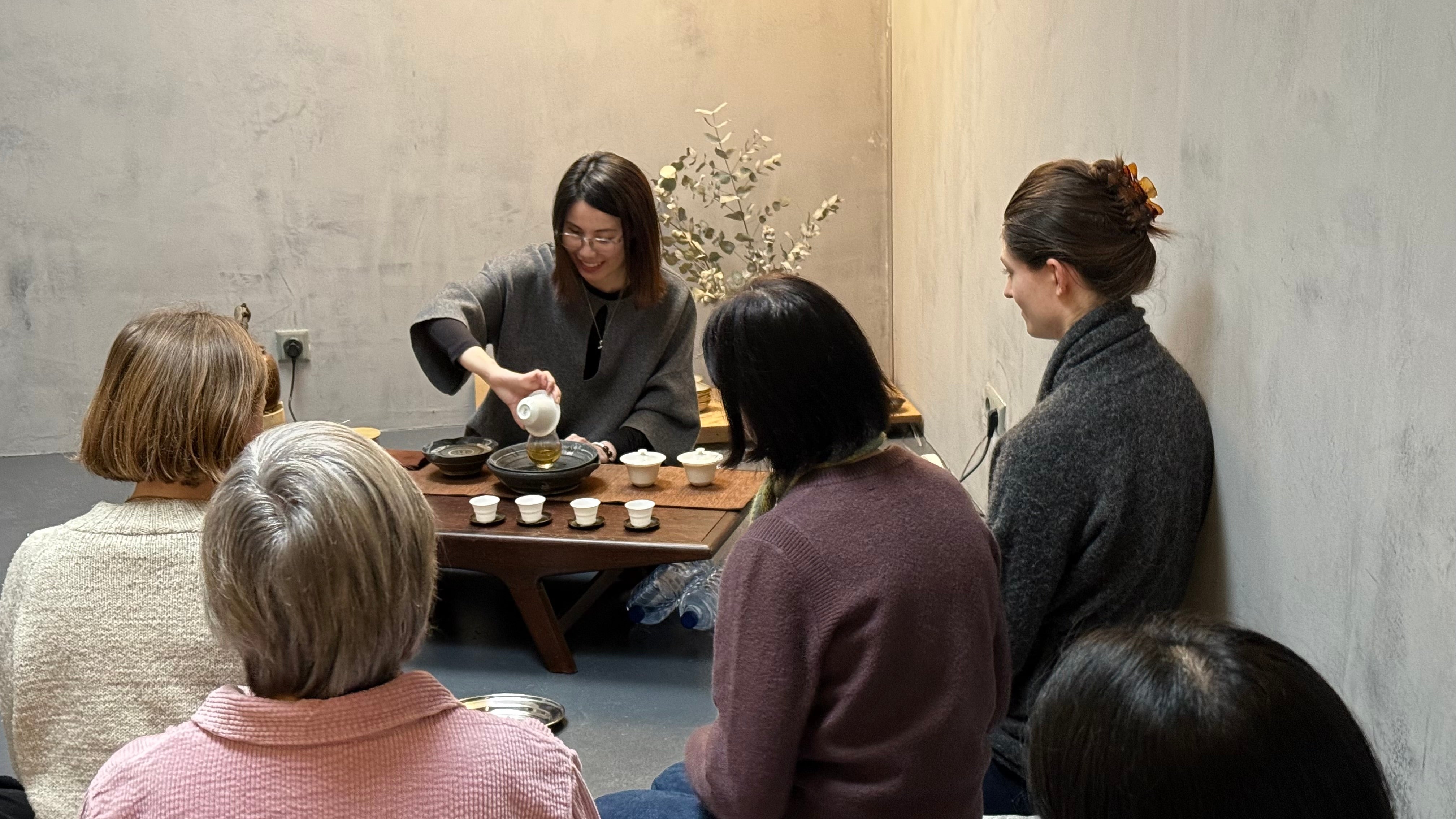 Group of people gathered around a table for a tea ceremony.